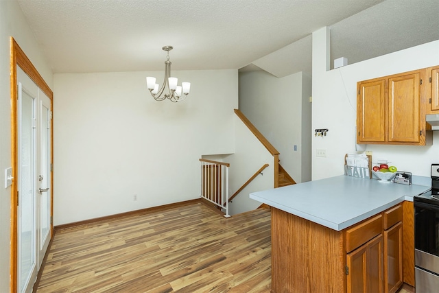 3719 SE 20th St, Des Moines, IA 50320 - kitchen featuring a peninsula, stainless steel range with electric cooktop, light wood-type flooring, a chandelier, and under cabinet range hood