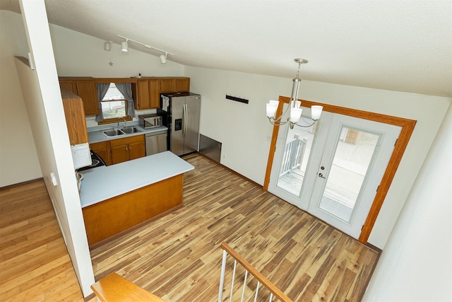 3719 SE 20th St, Des Moines, IA 50320 - kitchen with stainless steel appliances, brown cabinets, light wood-style flooring, and a chandelier