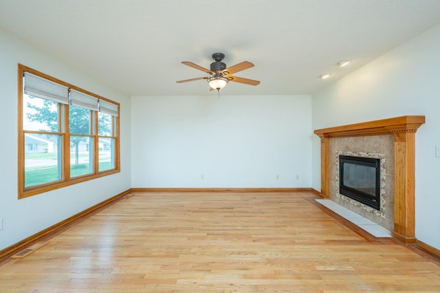 117 4th St NW, Altoona, IA 50009 - unfurnished living room featuring light wood-style floors, a tiled fireplace, and a ceiling fan