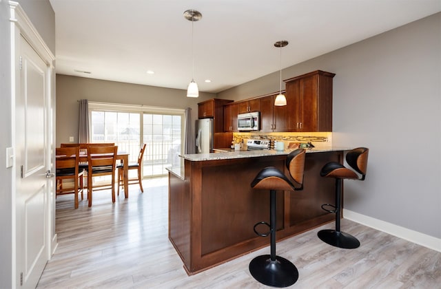 3600 SE Glenstone Dr Unit 308, Grimes, IA 50111 - kitchen featuring appliances with stainless steel finishes, light wood-style floors, light stone counters, a peninsula, and recessed lighting