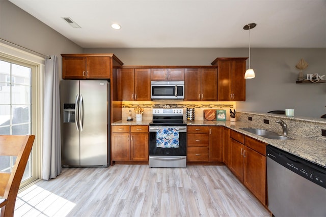 3600 SE Glenstone Dr Unit 308, Grimes, IA 50111 - kitchen featuring stainless steel appliances, light stone countertops, light wood-style floors, and hanging light fixtures