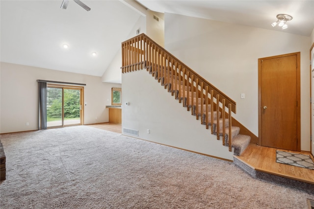 725 SE Peterson Dr, Ankeny, IA 50021 - unfurnished living room with high vaulted ceiling, stairs, carpet flooring, and a ceiling fan