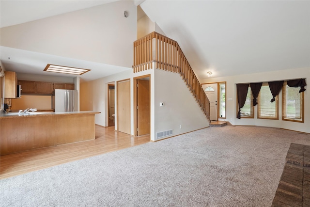 725 SE Peterson Dr, Ankeny, IA 50021 - unfurnished living room with light carpet, high vaulted ceiling, and stairs