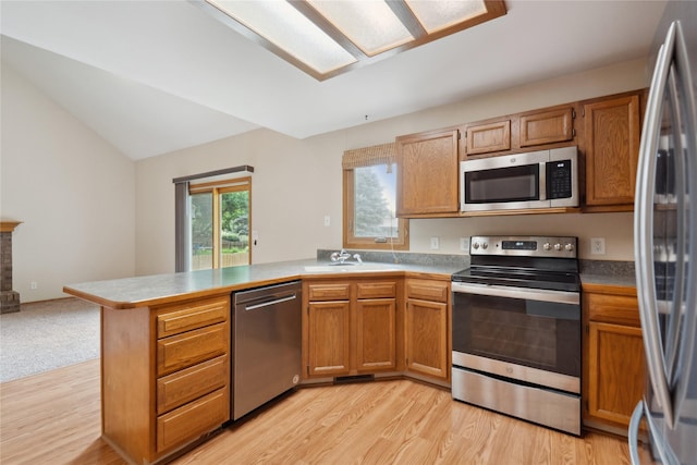 725 SE Peterson Dr, Ankeny, IA 50021 - kitchen with stainless steel appliances, a peninsula, light wood finished floors, vaulted ceiling, and brown cabinetry