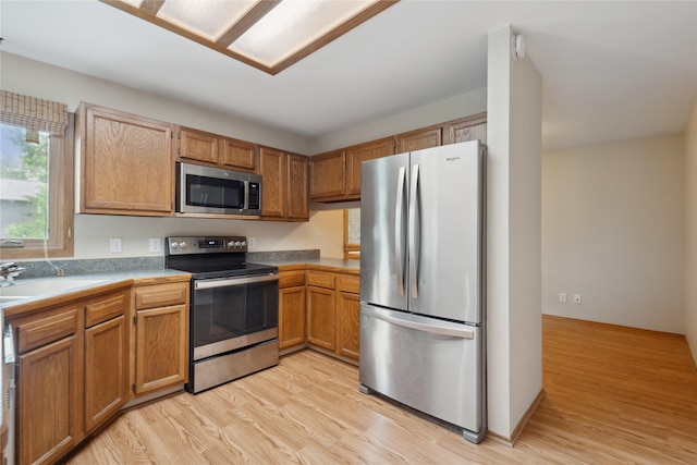 725 SE Peterson Dr, Ankeny, IA 50021 - kitchen with appliances with stainless steel finishes, light wood-style floors, light countertops, and brown cabinetry