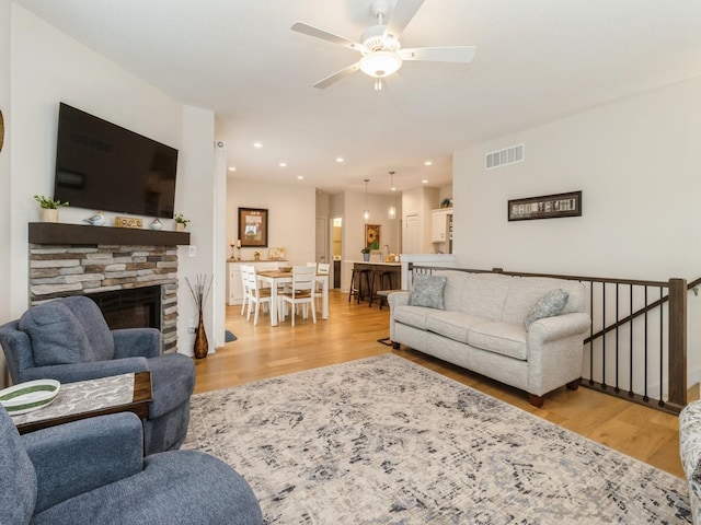 2206 SW Westwood St, Ankeny, IA 50023 - living room with wood finished floors, a ceiling fan, a stone fireplace, and recessed lighting