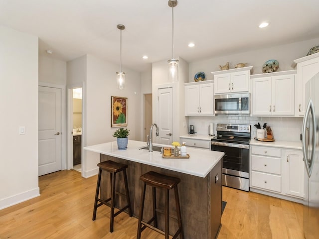 2206 SW Westwood St, Ankeny, IA 50023 - kitchen featuring stainless steel appliances, light wood finished floors, decorative backsplash, light countertops, and white cabinetry
