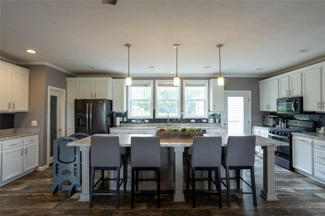 2006 10th St, Eldora, IA 50627 - kitchen featuring black appliances, tasteful backsplash, white cabinets, a kitchen island, and ornamental molding