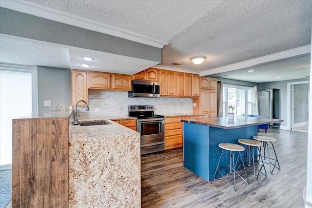 911 E 1st Ave, Indianola, IA 50125 - kitchen with stainless steel appliances, a textured ceiling, dark wood-style flooring, decorative backsplash, and a breakfast bar area