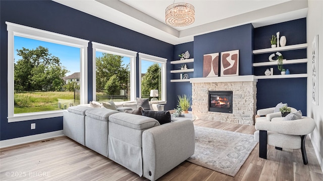 780 NE Badger Ln, Waukee, IA 50263 - living room featuring a fireplace, built in shelves, light wood-style flooring, and a raised ceiling