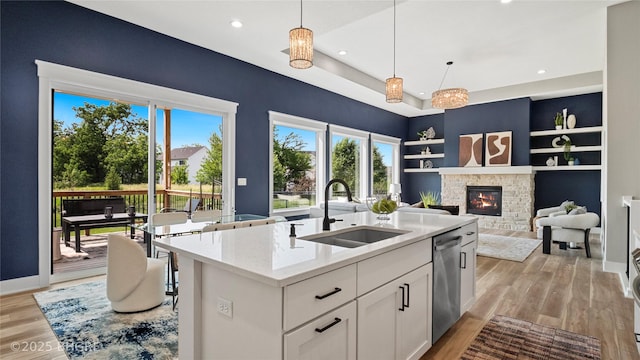 780 NE Badger Ln, Waukee, IA 50263 - kitchen with stainless steel dishwasher, a stone fireplace, white cabinets, light wood-style flooring, and recessed lighting