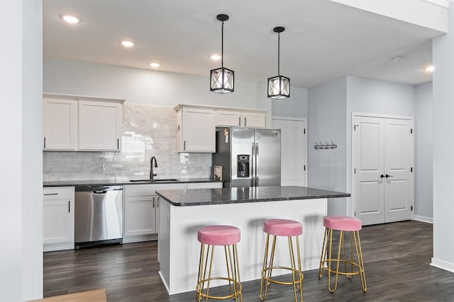 481 10th St, Waukee, IA 50263 - kitchen featuring appliances with stainless steel finishes, tasteful backsplash, a kitchen bar, dark wood finished floors, and recessed lighting