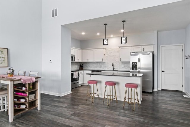 481 10th St, Waukee, IA 50263 - kitchen with stainless steel appliances, dark wood finished floors, decorative backsplash, a center island, and a kitchen bar