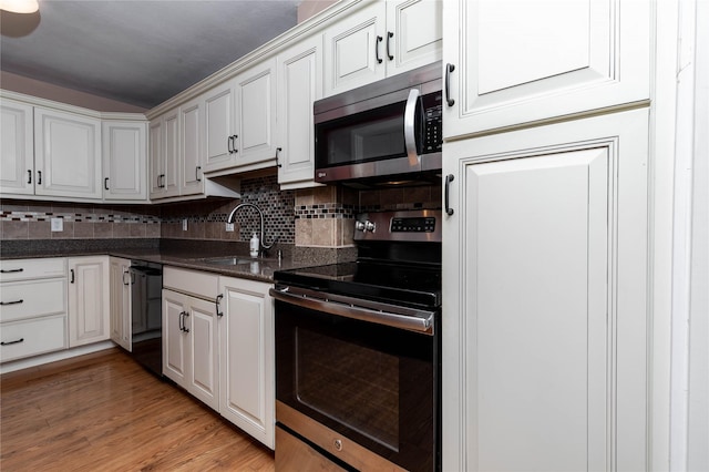 3663 Grand Ave Unit 604, Des Moines, IA 50312 - kitchen featuring appliances with stainless steel finishes, decorative backsplash, light wood-style floors, and white cabinetry