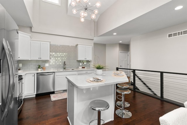 14186 Pinnacle Pointe Dr Unit 86, Clive, IA 50325 - kitchen with stainless steel appliances, light countertops, dark wood-style flooring, white cabinets, and a breakfast bar