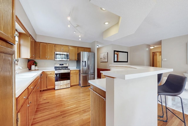 4855 Coachlight Dr, West Des Moines, IA 50265 - kitchen featuring appliances with stainless steel finishes, light wood finished floors, light countertops, a breakfast bar, and a kitchen island