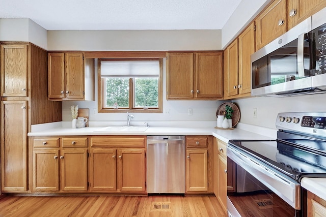 4855 Coachlight Dr, West Des Moines, IA 50265 - kitchen with stainless steel appliances, brown cabinets, light countertops, and light wood-type flooring