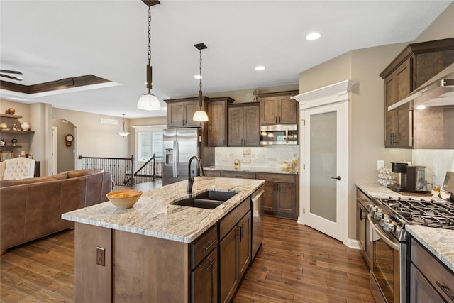 800 NE Badger Ln, Waukee, IA 50263 - kitchen featuring appliances with stainless steel finishes, open floor plan, dark wood finished floors, decorative backsplash, and a center island with sink