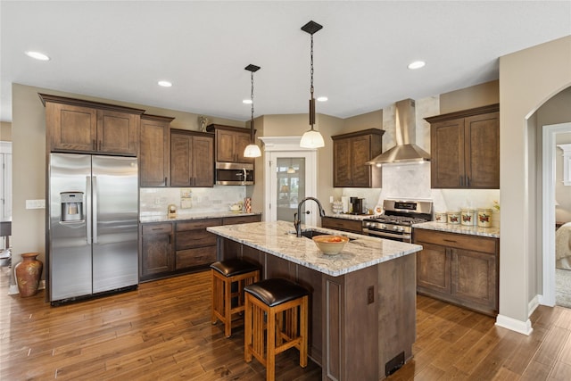800 NE Badger Ln, Waukee, IA 50263 - kitchen featuring appliances with stainless steel finishes, wall chimney range hood, dark wood-style floors, a center island with sink, and recessed lighting