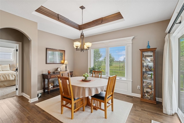 800 NE Badger Ln, Waukee, IA 50263 - dining room featuring a raised ceiling, arched walkways, wood finished floors, a chandelier, and ornamental molding