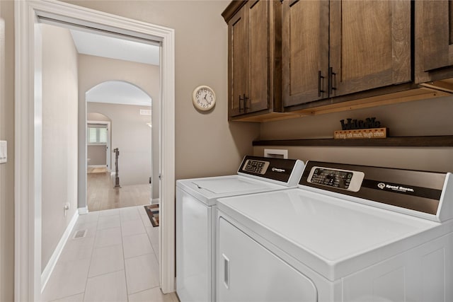 800 NE Badger Ln, Waukee, IA 50263 - washroom with cabinet space, washing machine and clothes dryer, arched walkways, and light tile patterned flooring