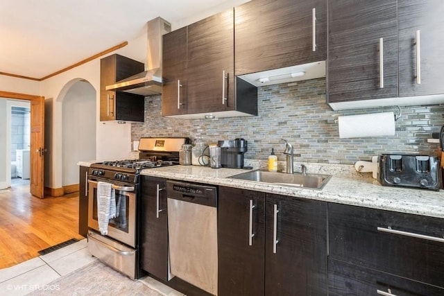 2417 Maryland Pike, Des Moines, IA 50310 - kitchen featuring appliances with stainless steel finishes, wall chimney range hood, arched walkways, tasteful backsplash, and light stone countertops