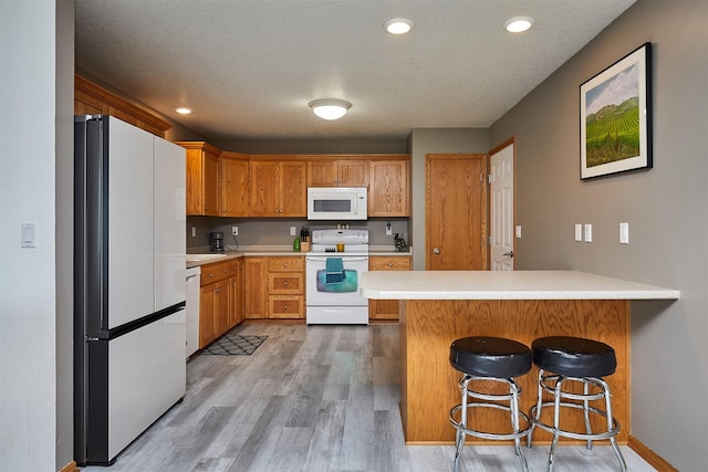 2014 Vista View Dr, Granger, IA 50109 - kitchen featuring white appliances, a peninsula, light countertops, light wood-type flooring, and a breakfast bar