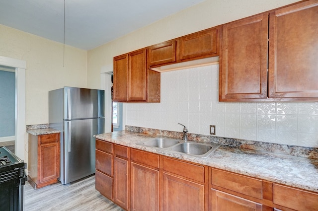 2736 College Ave, Des Moines, IA 50311 - kitchen with freestanding refrigerator, light wood-style floors, black range oven, brown cabinetry, and tasteful backsplash