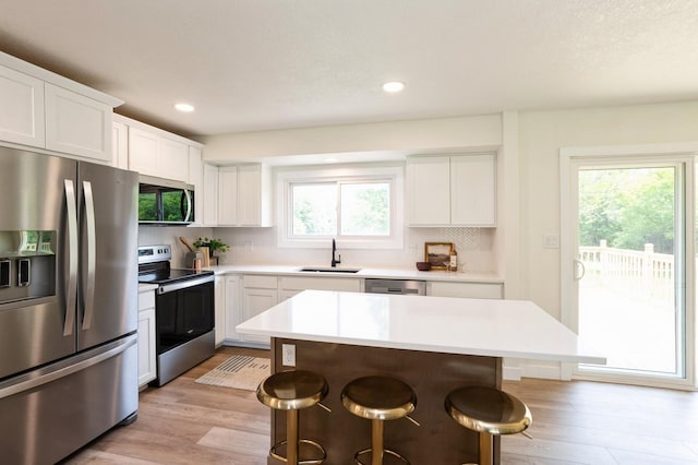 8501 NW Beaver Dr, Johnston, IA 50131 - kitchen featuring appliances with stainless steel finishes, a breakfast bar, light wood finished floors, tasteful backsplash, and light countertops
