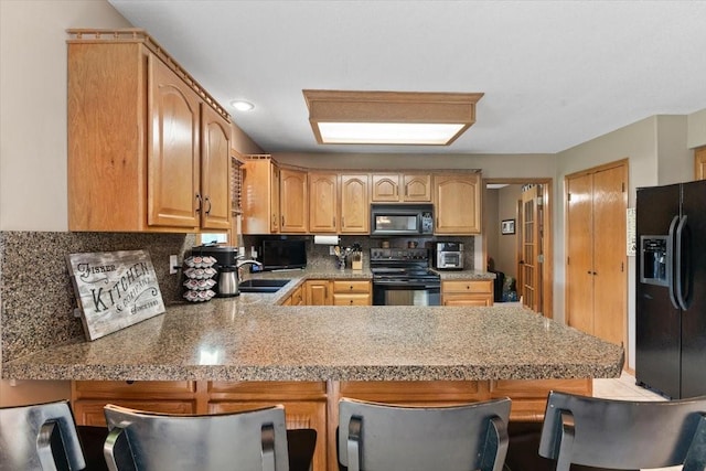1305 NW Wagner Blvd, Ankeny, IA 50023 - kitchen featuring black appliances, a peninsula, a breakfast bar area, decorative backsplash, and recessed lighting