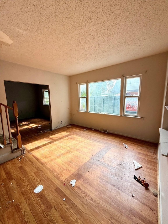 2216 Logan Ave, Des Moines, IA 50317 - unfurnished living room with a textured ceiling and wood finished floors