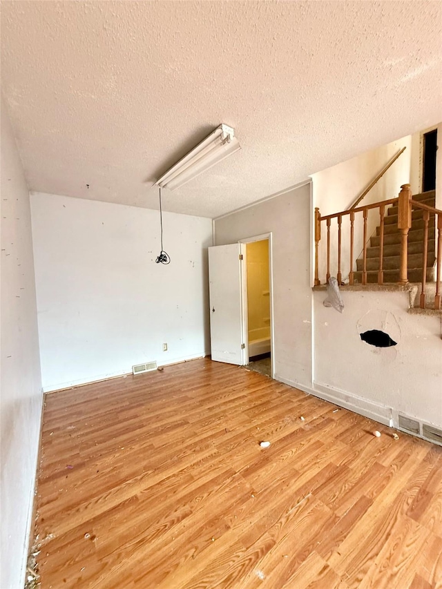 2216 Logan Ave, Des Moines, IA 50317 - empty room featuring wood finished floors, a textured ceiling, and attic access