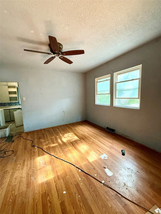 2216 Logan Ave, Des Moines, IA 50317 - unfurnished living room with wood finished floors, a textured ceiling, and a ceiling fan