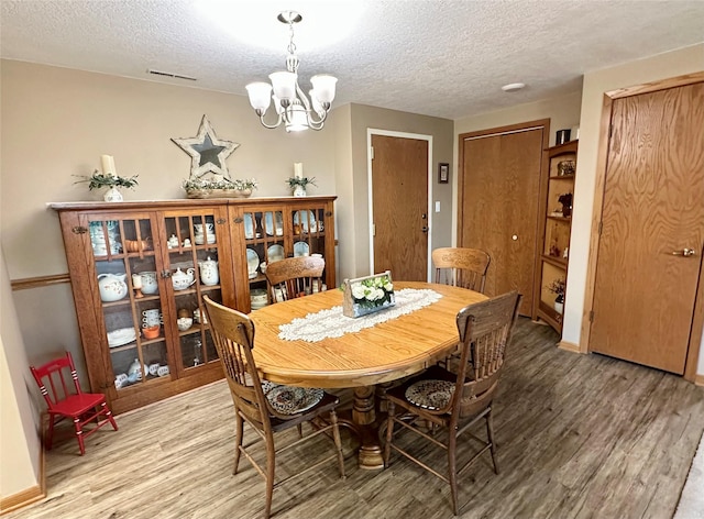 2005 Spring St Unit U203, Grinnell, IA 50112 - dining space with light wood-style flooring, a textured ceiling, and a chandelier
