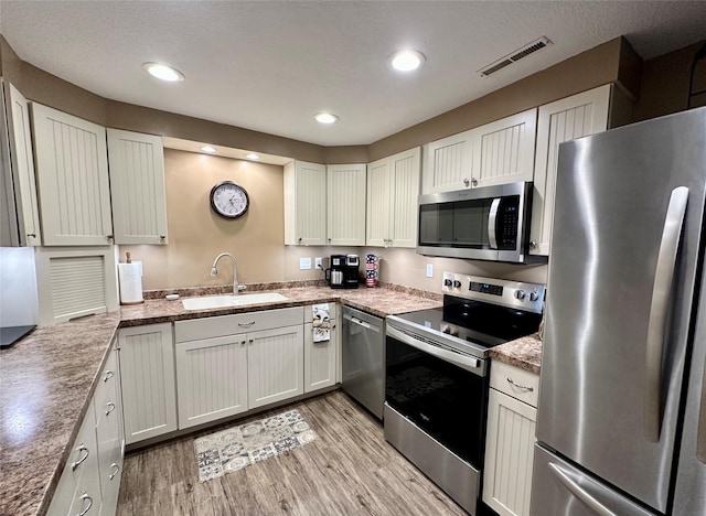 2005 Spring St Unit U203, Grinnell, IA 50112 - kitchen with appliances with stainless steel finishes, light wood finished floors, white cabinets, and recessed lighting