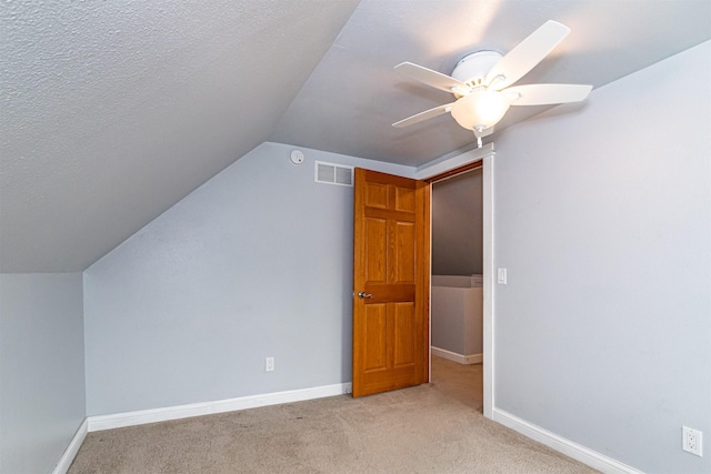 1229 9th St, Nevada, IA 50201 - additional living space with light colored carpet, vaulted ceiling, ceiling fan, and a textured ceiling