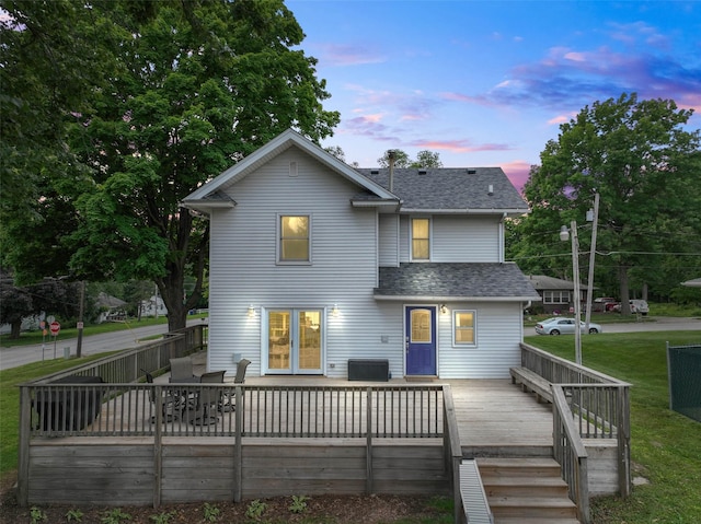 2800 E Douglas Ave, Des Moines, IA 50317 - back of house at dusk with roof with shingles, a wooden deck, and a lawn