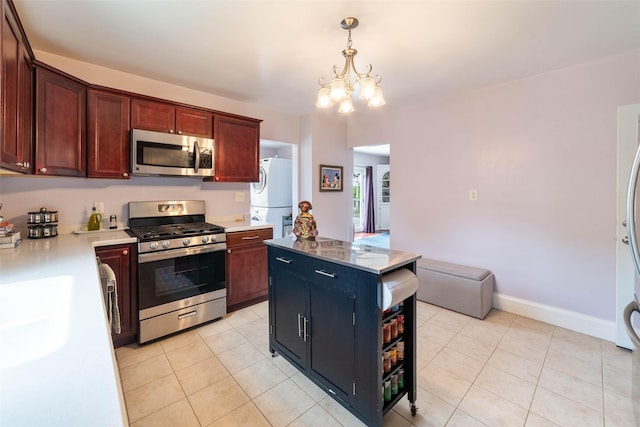 2800 E Douglas Ave, Des Moines, IA 50317 - kitchen with stainless steel appliances, stacked washer / drying machine, a chandelier, light tile patterned flooring, and hanging light fixtures