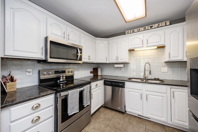 905 SE Meadowlark Dr, Grimes, IA 50111 - kitchen featuring stainless steel appliances, tasteful backsplash, white cabinetry, light tile patterned flooring, and dark stone countertops