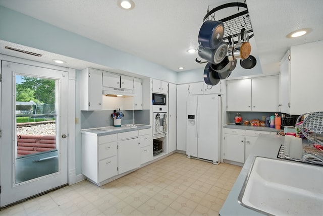 455 NW 2nd St, Earlham, IA 50072 - kitchen featuring white appliances, white cabinets, under cabinet range hood, light countertops, and recessed lighting