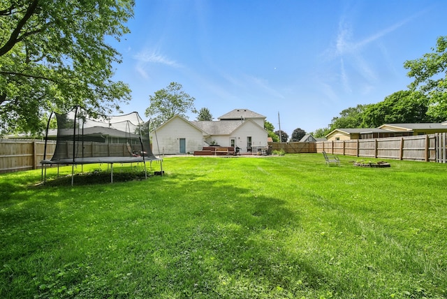 455 NW 2nd St, Earlham, IA 50072 - fenced backyard featuring a trampoline, a wooden deck, and a fire pit