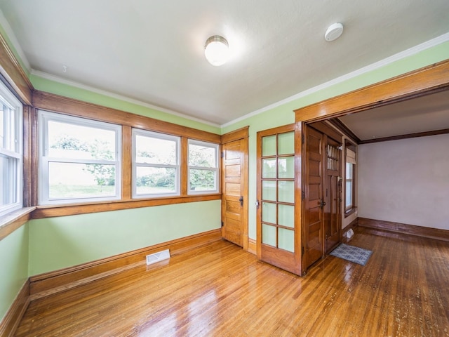 3324 Rollins Ave, Des Moines, IA 50312 - empty room featuring wood finished floors, plenty of natural light, crown molding, and a smoke detector