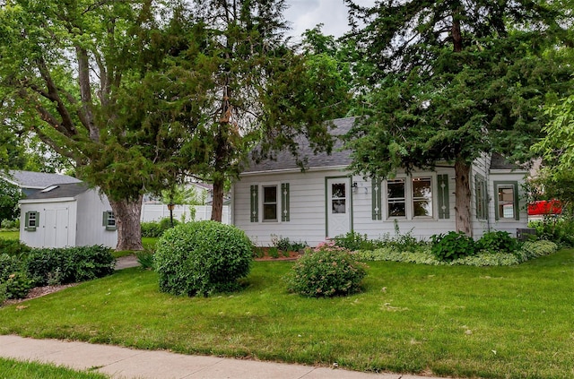 16 E Leach Ave, Des Moines, IA 50315 - view of front of home featuring a front lawn, a shingled roof, and a storage shed