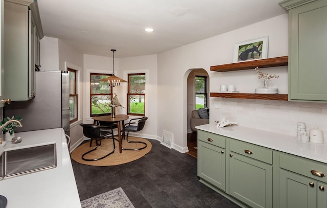 16 E Leach Ave, Des Moines, IA 50315 - kitchen featuring green cabinets, arched walkways, freestanding refrigerator, light countertops, and decorative backsplash