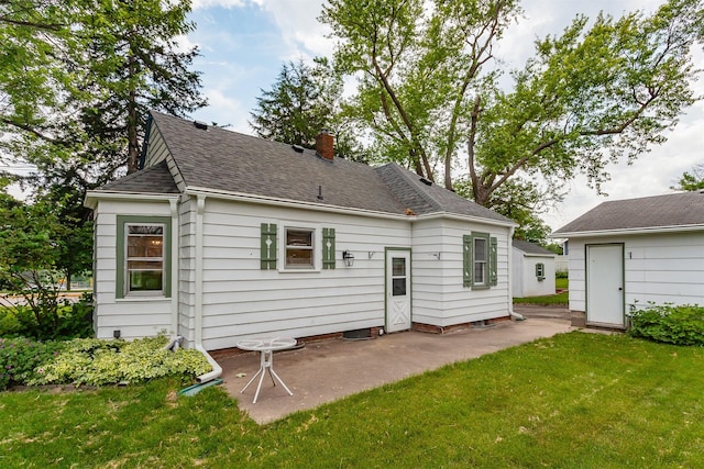 16 E Leach Ave, Des Moines, IA 50315 - rear view of property featuring a patio, a yard, a storage unit, a chimney, and a shingled roof