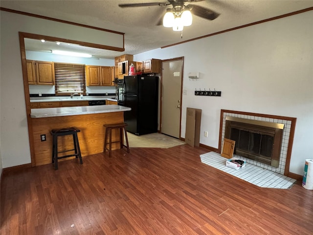 2601 Sherwood Dr, Des Moines, IA 50310 - kitchen with freestanding refrigerator, brown cabinets, light wood-style floors, ceiling fan, and a peninsula