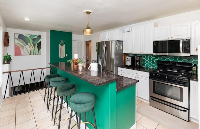 6771 College Ave, Windsor Heights, IA 50324 - kitchen with stainless steel appliances, light tile patterned floors, white cabinets, and a breakfast bar