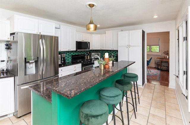 6771 College Ave, Windsor Heights, IA 50324 - kitchen with stainless steel fridge, stove, white cabinets, light tile patterned floors, and dark stone counters
