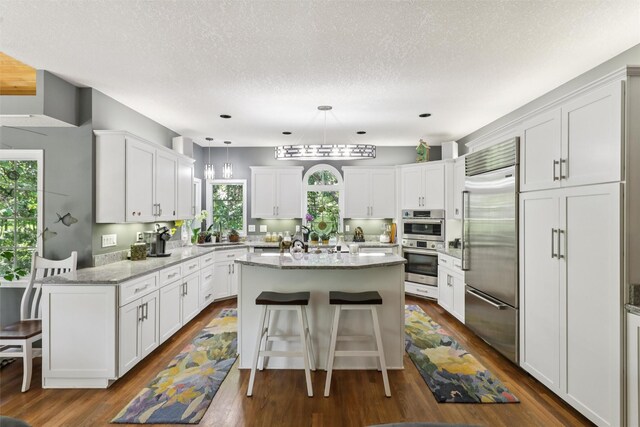 4210 Beaver Hills Dr, Des Moines, IA 50310 - kitchen with appliances with stainless steel finishes, a breakfast bar, white cabinets, plenty of natural light, and a textured ceiling