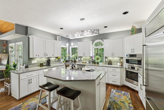4210 Beaver Hills Dr, Des Moines, IA 50310 - kitchen with stainless steel appliances, a kitchen island, white cabinets, dark wood finished floors, and a textured ceiling